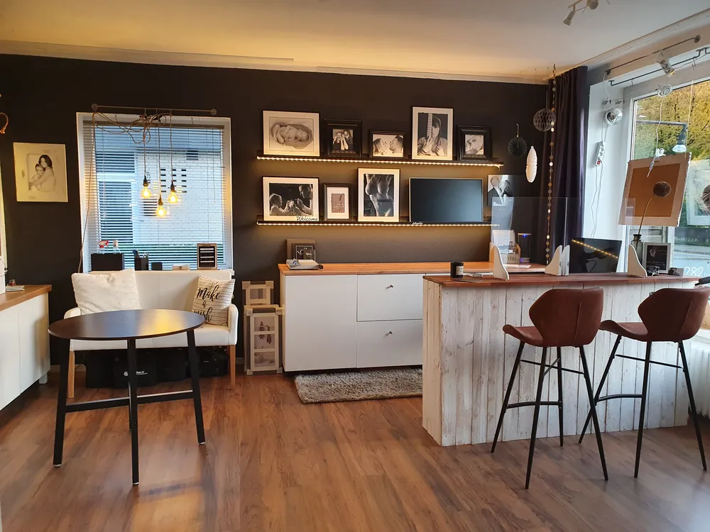 Empfangsbereich mit Theke, Barhockern und beleuchteter Bilderwand