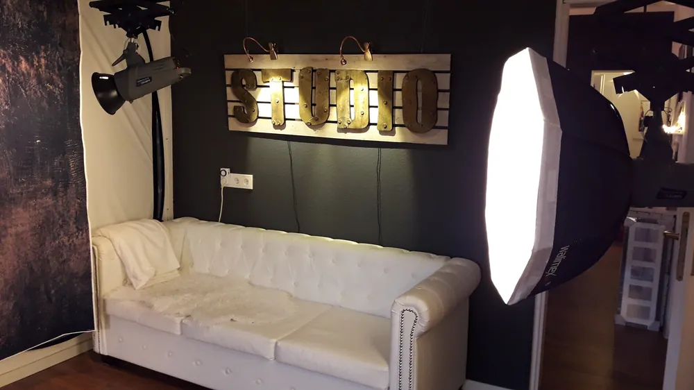 Weißes Chesterfield-Sofa unter dem beleuchteten Studio-Schild