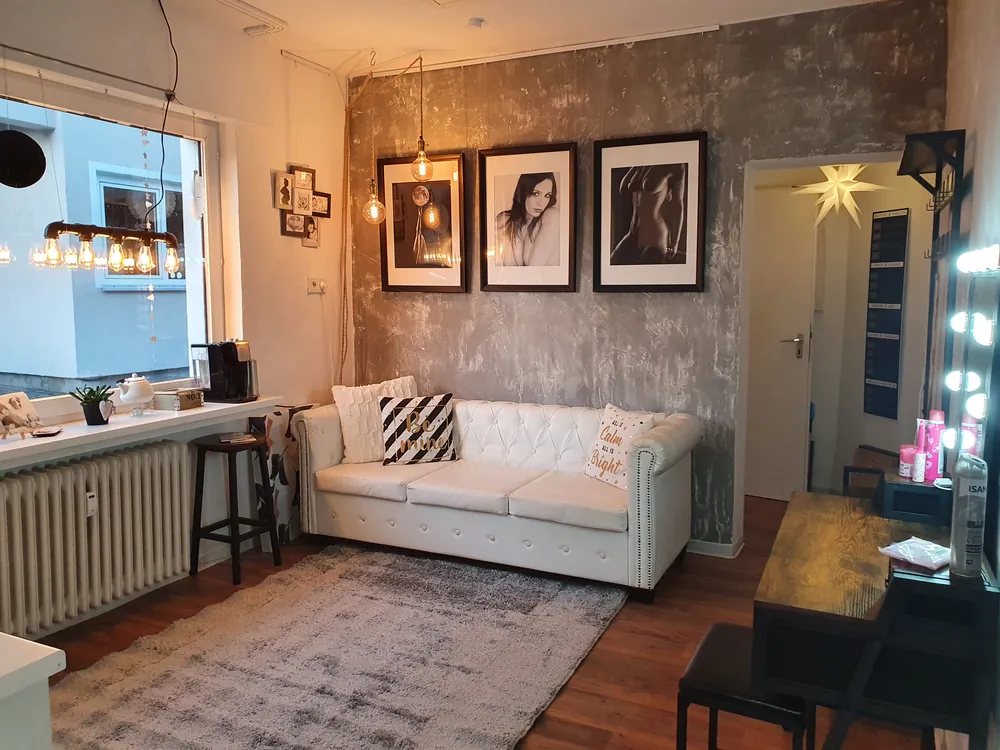 Lounge-Ecke mit Sofa, Kaffeemaschine und gerahmten Arbeiten